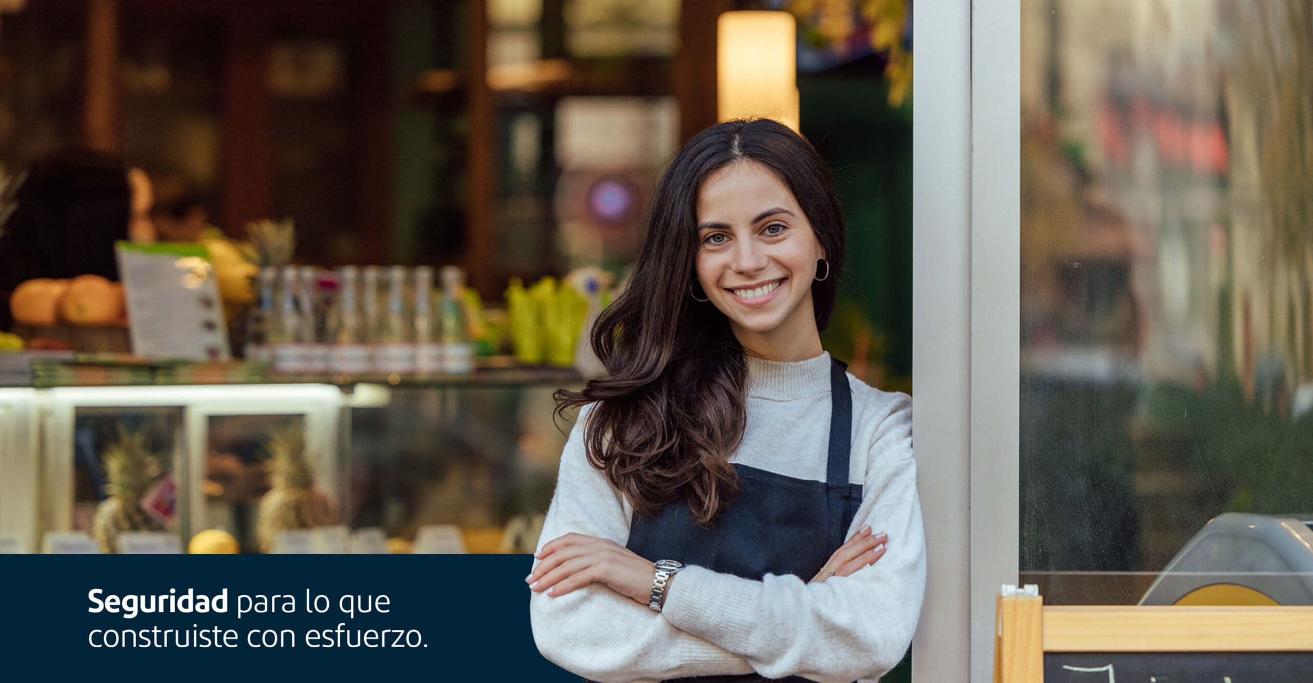 Dueña de negocio en la puerta y mensaje que lee 'Seguridad para lo que construiste con esfuerzo'.